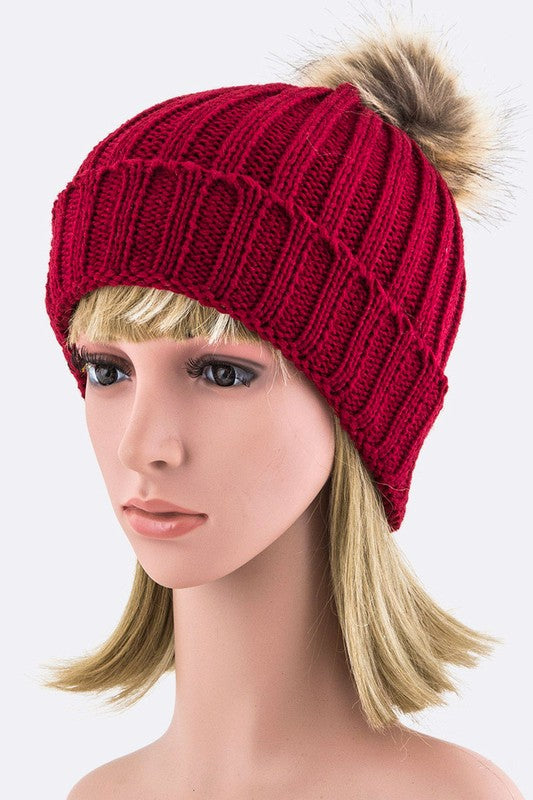 Vibrant red ribbed knit beanie with a faux fur pom, perfect for colder days.
