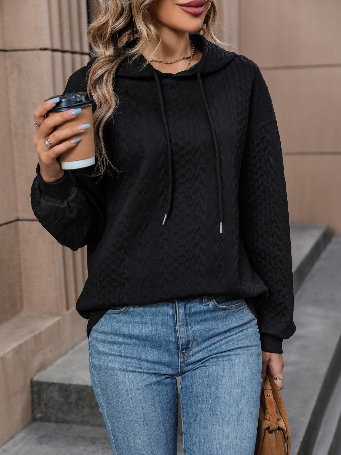 Black pullover hoodie with a cable knit pattern and adjustable drawstring.
