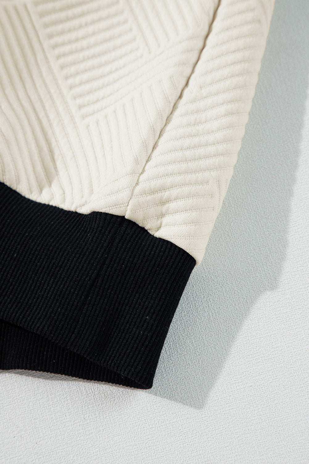 A relaxed-fit textured beige pullover with black trim, perfect for layering and fall fashion.

