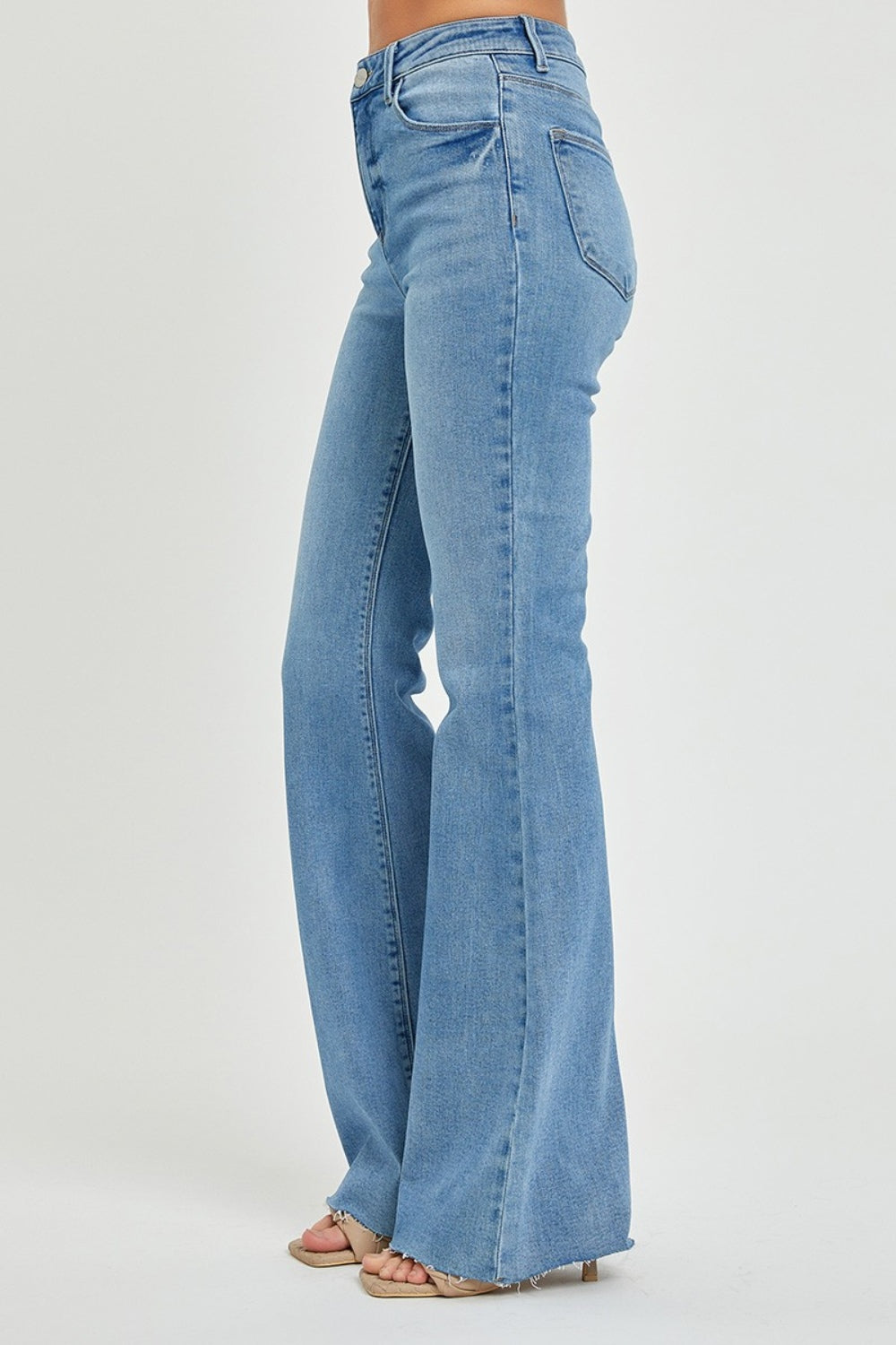 Side view of RISEN High Rise Raw Cut Hem Bootcut Jeans highlighting bootcut style.