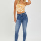 Model wearing RISEN Mid Rise Ankle Skinny Jeans, styled with a crop top.