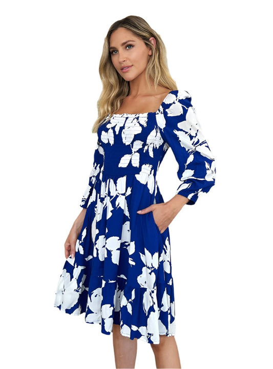 A vibrant royal blue midi dress with white floral print and smocked bodice.

