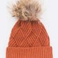 Rust-colored knit winter hat with faux fur pom detail
