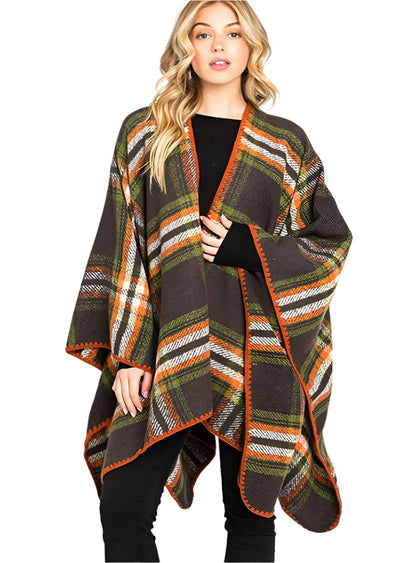 Woman wearing green plaid wrap shawl with orange trim over black top.
