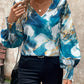 Satin V-neck blouse with marble print in blue, white, and gold tones for a stylish look.
