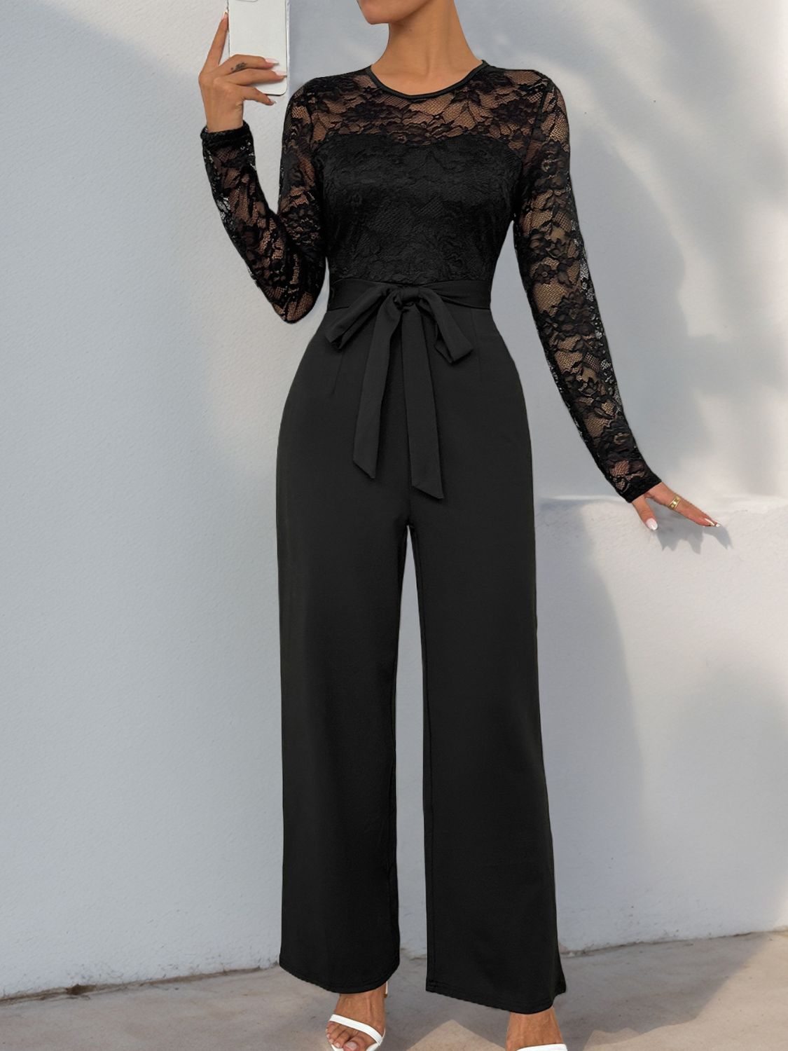 Black jumpsuit with semi-sheer lace bodice and high-waist tie.
