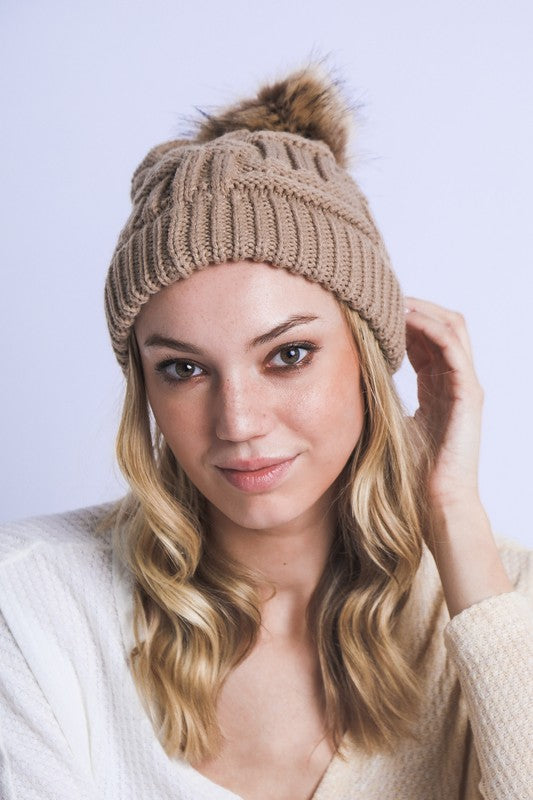 Soft tan cable knit beanie with luxurious fur pom accent

