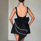 Sleeveless black dress with pearl detailing and a large back bow.