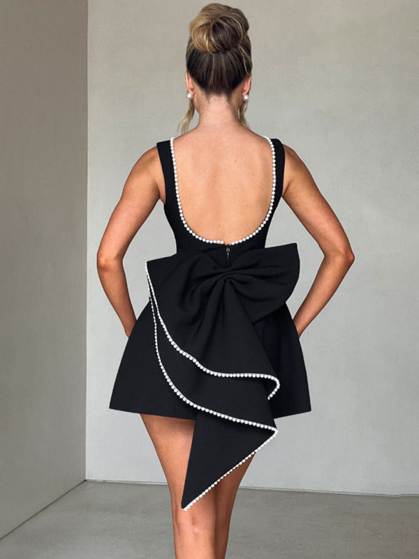 Sleeveless black dress with pearl detailing and a large back bow.