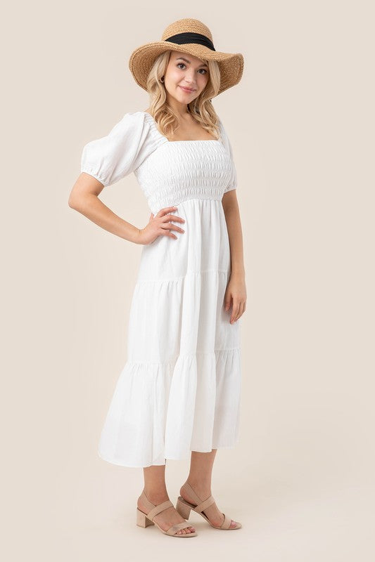 Whimsical women's white midi dress with puff sleeves and a smocked bodice.
