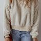 Cozy fleece hoodie in neutral beige with dropped shoulders, great for layering.
