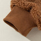 Soft fleece sherpa fabric on a women's brown jacket with snap buttons.