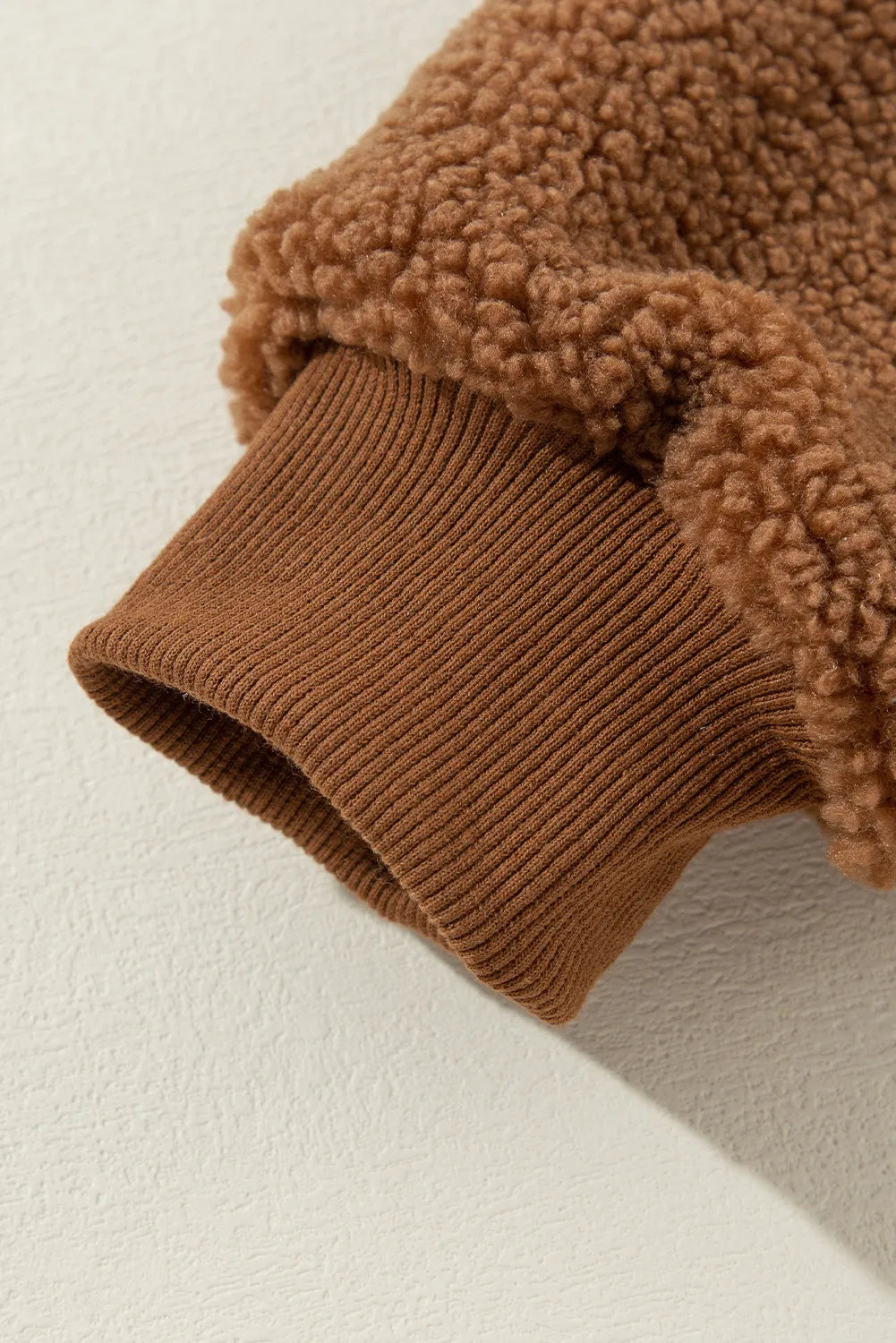 Soft fleece sherpa fabric on a women's brown jacket with snap buttons.