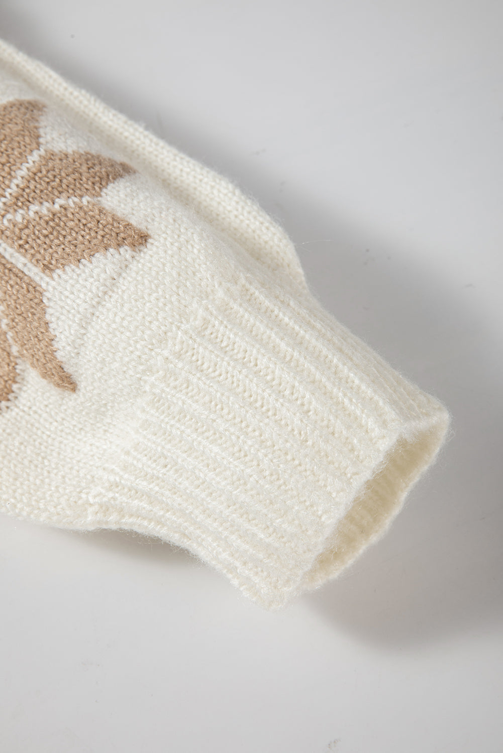 Close-up of an ivory knit sweater with a festive snowflake pattern, designed for warmth and comfort during the holidays.