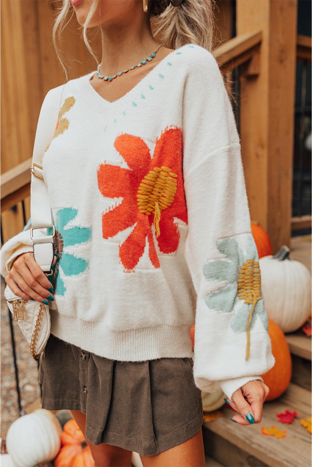 Woman in an ivory sweater with bold flower patterns, styled casually | boho aesthetic
