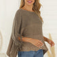 Neutral taupe knit poncho with a relaxed drape and fringe hem for added style.