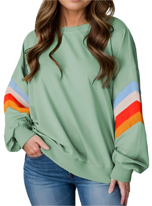 Woman modeling a sage green sweatshirt with chevron striped sleeves for a stylish casual look.
