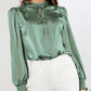 Sophisticated green blouse styled with white pants for a chic look.
