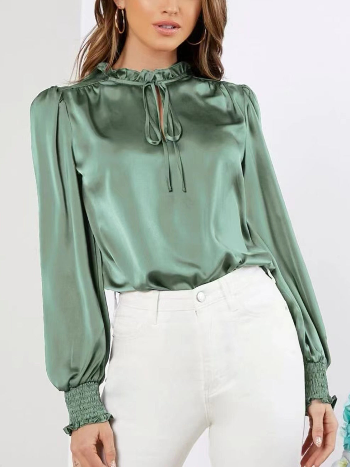 Sophisticated green blouse styled with white pants for a chic look.
