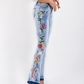 Side view of floral embroidered flare jeans in light wash denim.
