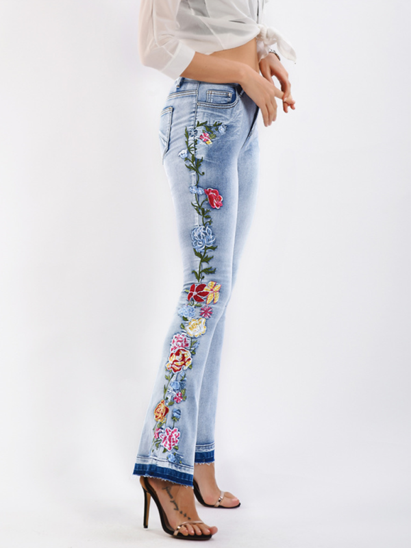 Side view of floral embroidered flare jeans in light wash denim.
