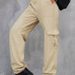 Side profile of tan high-waist cargo pants with functional pockets.
