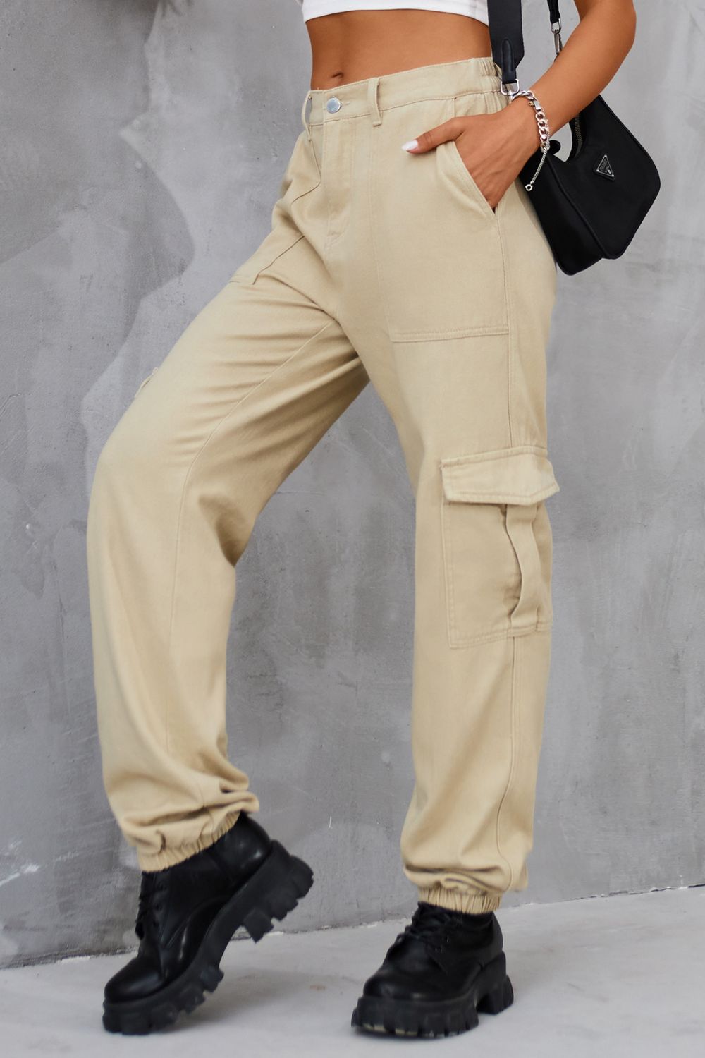 Side profile of tan high-waist cargo pants with functional pockets.
