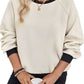 Front view of a beige pullover with black contrast trim, featuring a textured geometric design.