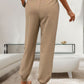 Back view of khaki tied elastic waist pants with relaxed fit and cuffed ankles
