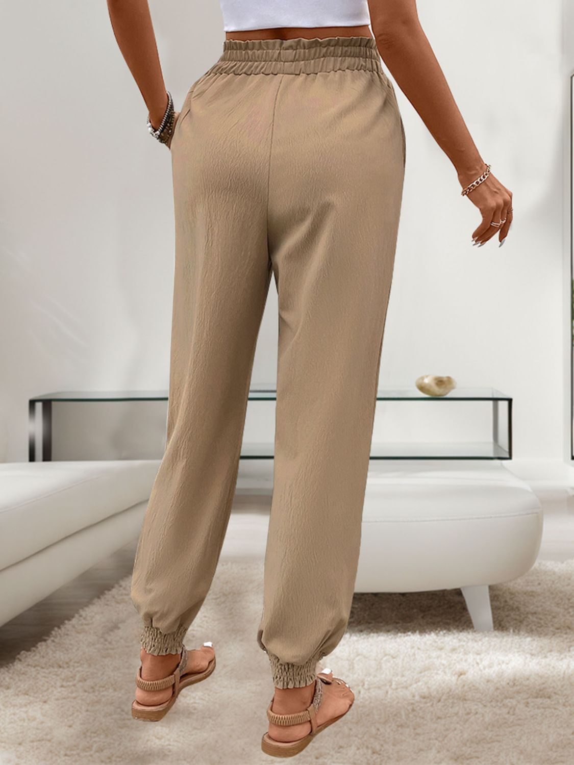 Back view of khaki tied elastic waist pants with relaxed fit and cuffed ankles
