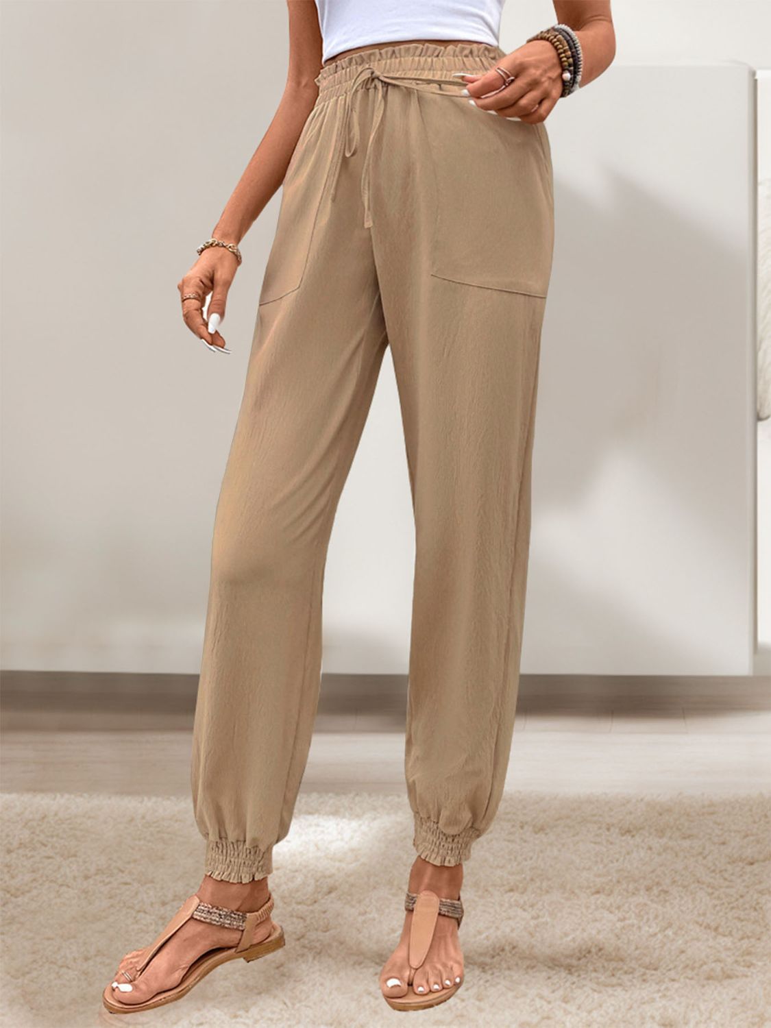 Side view of khaki tied elastic waist pants, styled with casual sandals
