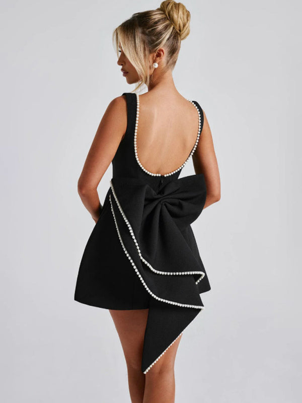 Timeless black A-line dress with elegant pearl accents and bow detailing.