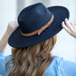 Black wide brim Panama hat with a tassel belt shown from the side profile.
