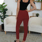 Trendy burgundy skinny pants featuring button accents on the waist.