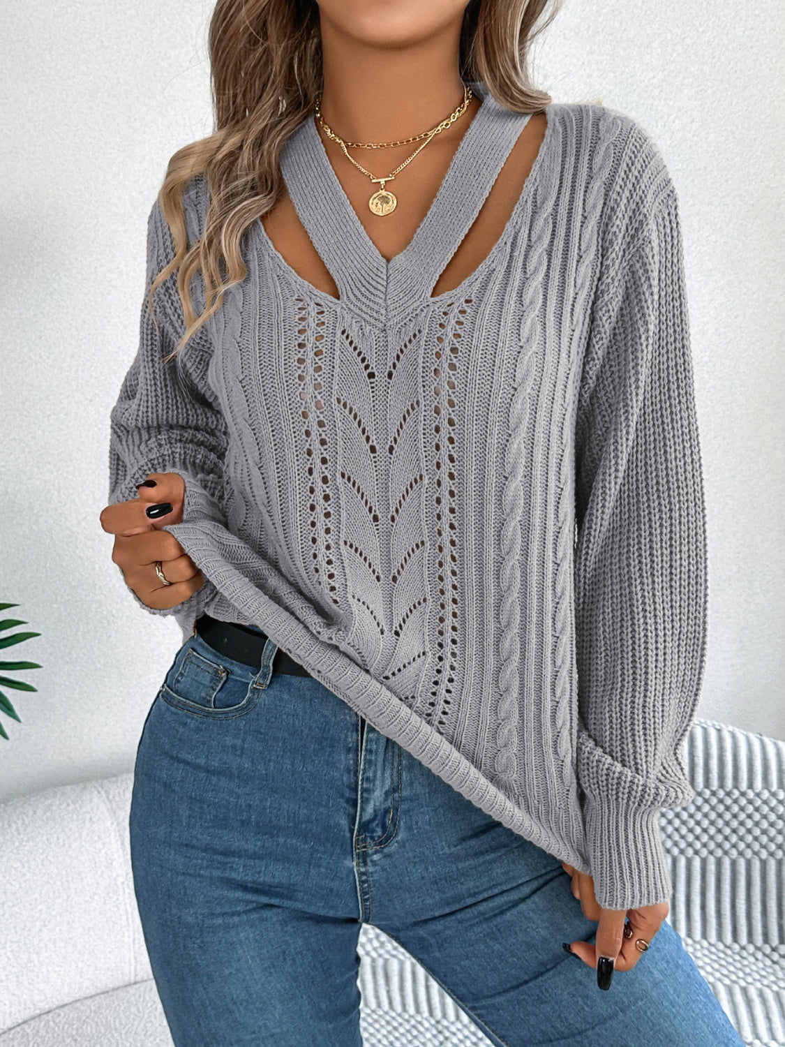 Gray cutout V-neck cable knit sweater paired with black pants