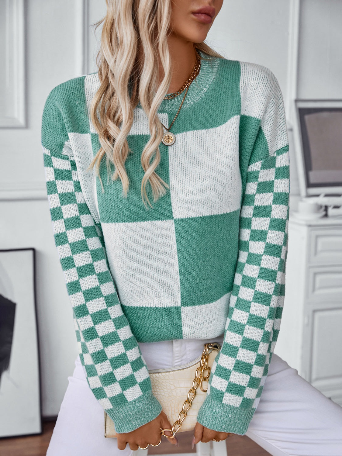 Woman in a turquoise patchwork sweater with checkered sleeves for added style.
