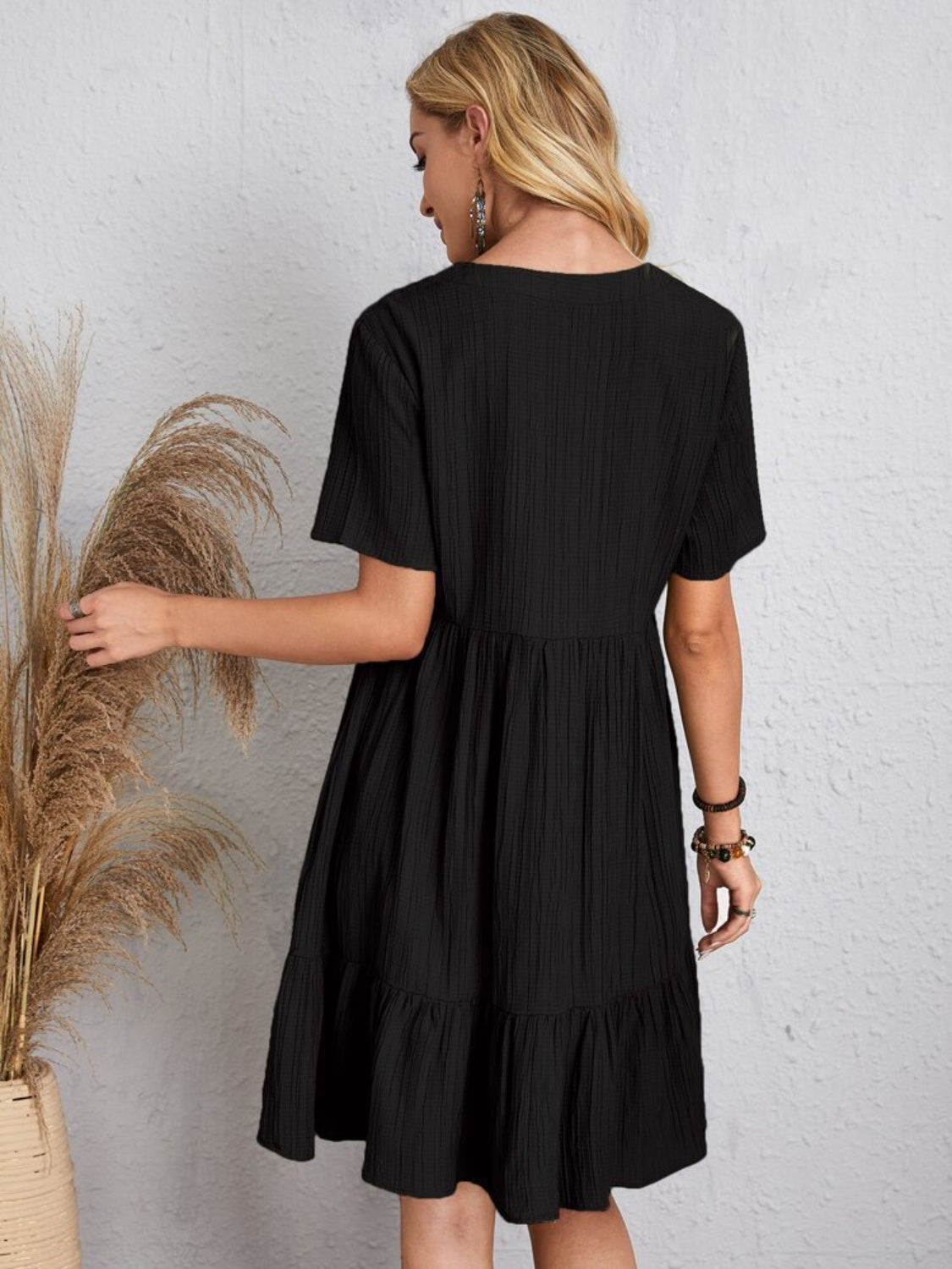 Black babydoll dress with a tiered hem and relaxed fit, perfect for warm weather
