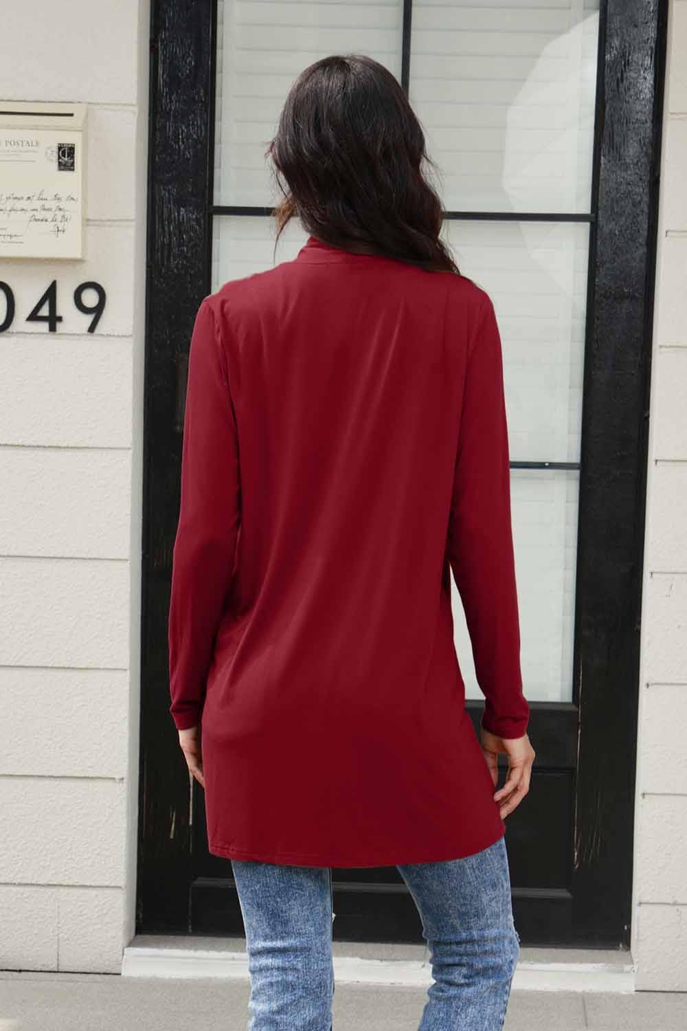 Back view of versatile red drape cardigan, styled with jeans.