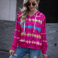 Woman wearing a vibrant pink tie-dye hooded sweatshirt with white drawstrings and raglan sleeves.
