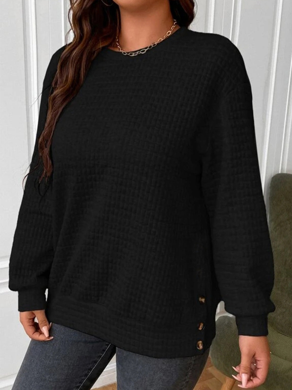 Black waffle-knit sweatshirt with a relaxed fit and side buttons for women.
