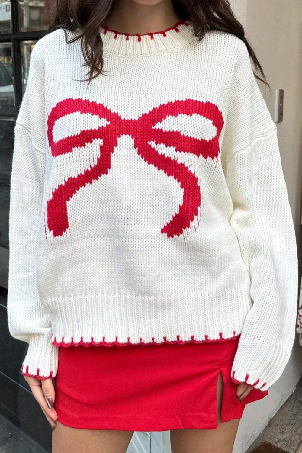 Front view of a white bow-knot knit sweater, perfect for cozy winter days with a fun bow design.

