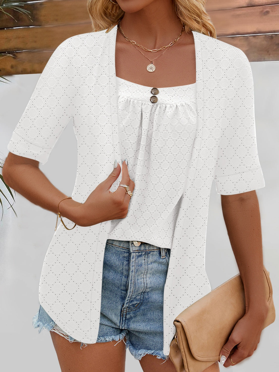 White faux layered top featuring an eyelet design and button accents