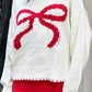 Close-up of a white knit sweater featuring a large bow design, adding charm to winter outfits.

