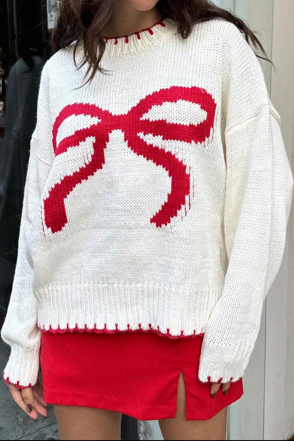 Close-up of a white knit sweater featuring a large bow design, adding charm to winter outfits.

