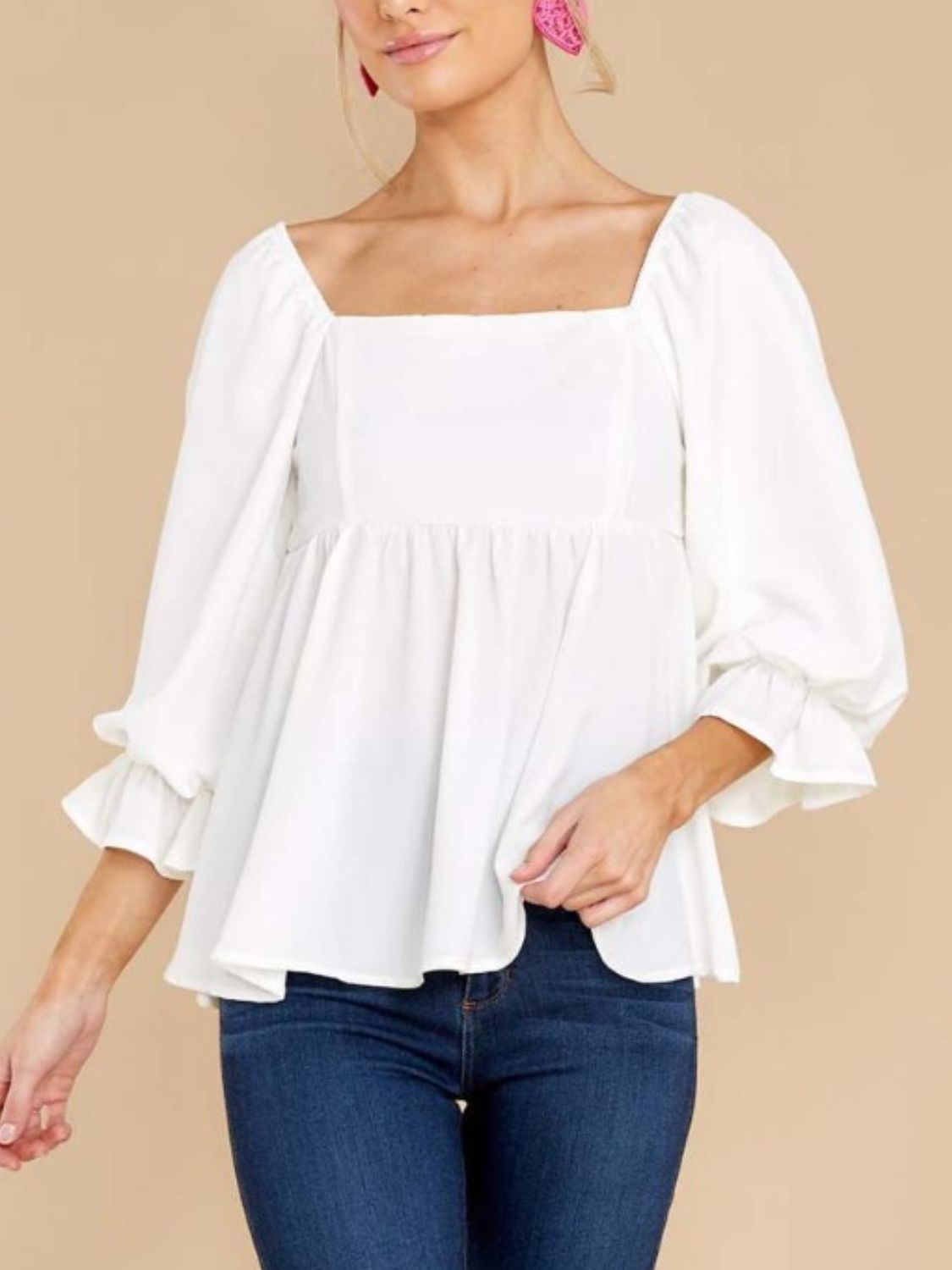 White ruffled babydoll blouse with square neckline, styled with jeans.
