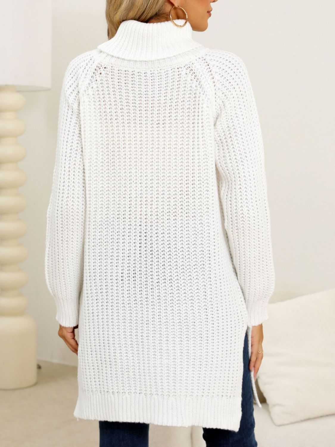 Woman wearing a cozy white turtleneck slit sweater.
