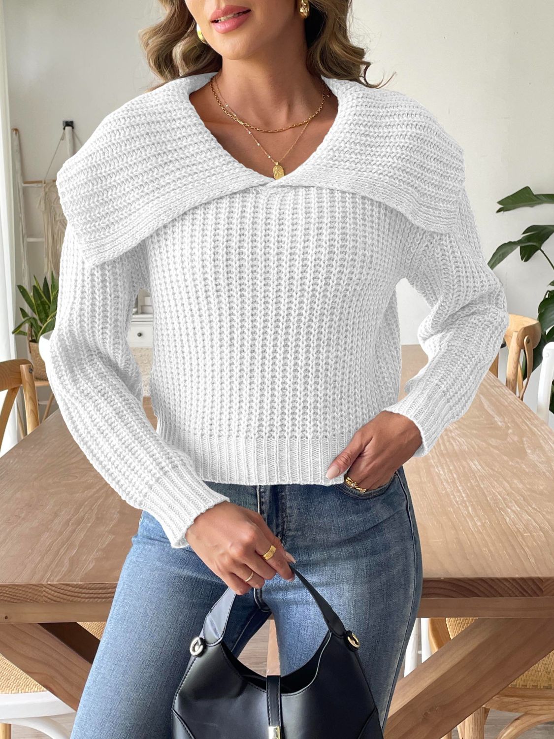 Woman wearing a white cable-knit wide collar sweater with jeans.
