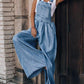 Relaxed-fit wide-leg denim overalls styled with a white tank top.
