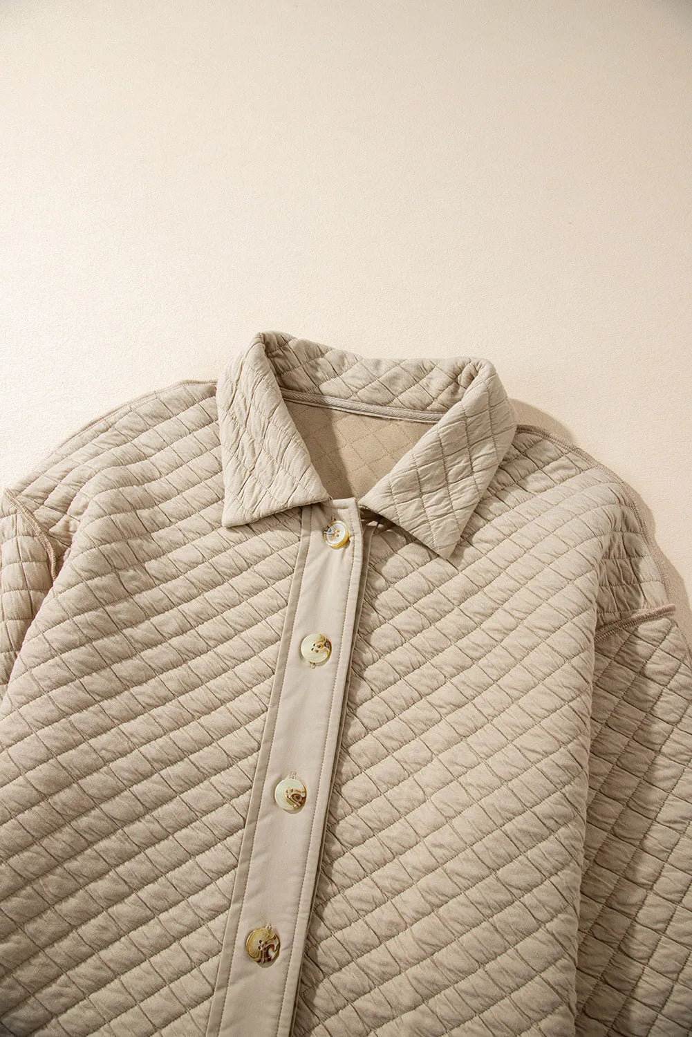 Close-up of quilted texture on cozy neutral jacket.
