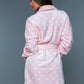 Close-up of a woman wearing a pink polka dot plush robe, showcasing the soft fabric.
